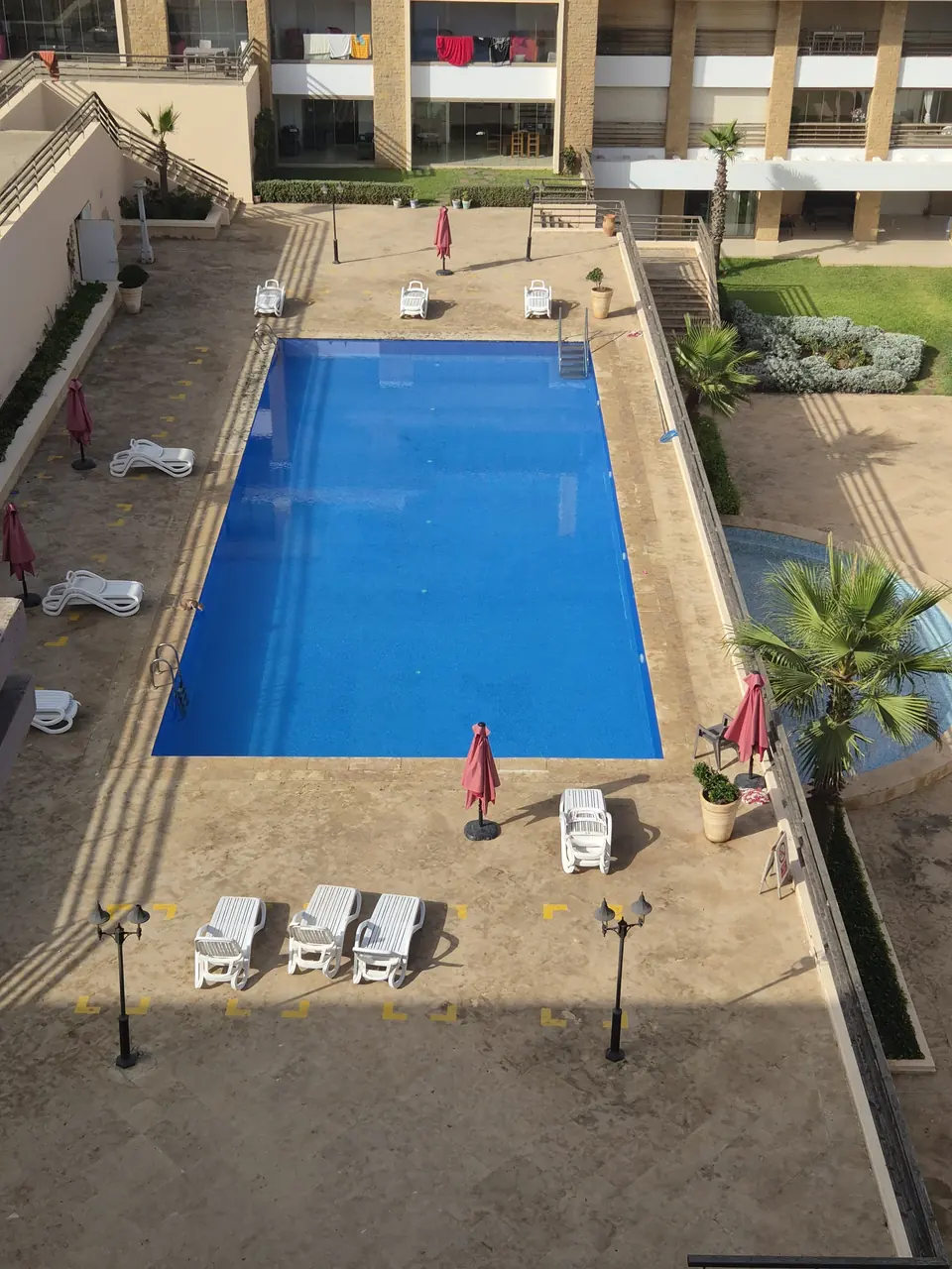 Une des trois piscines extérieures de la résidence, avec transats