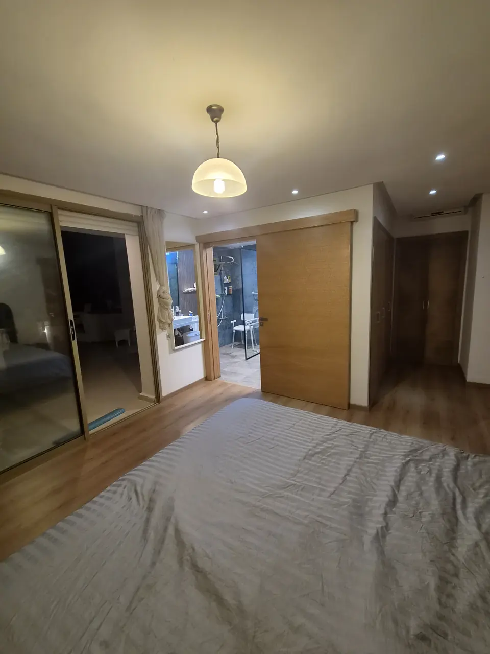 Suite parentale vue depuis le lit, baie vitrée et porte coulissante vers la salle de bain