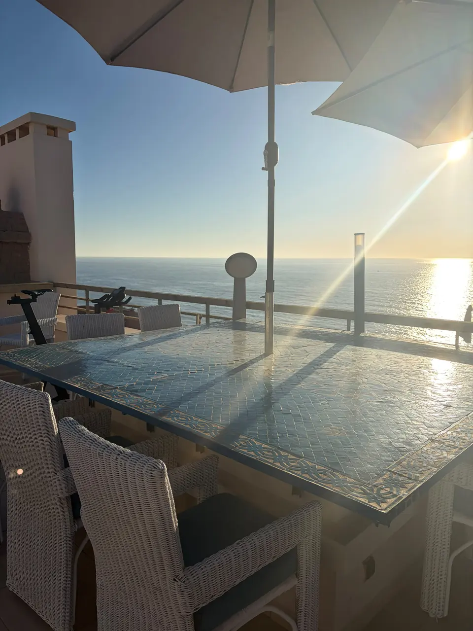 Grande table d’extérieur au bord de la terrasse, l’océan juste derrière comme depuis un bateau