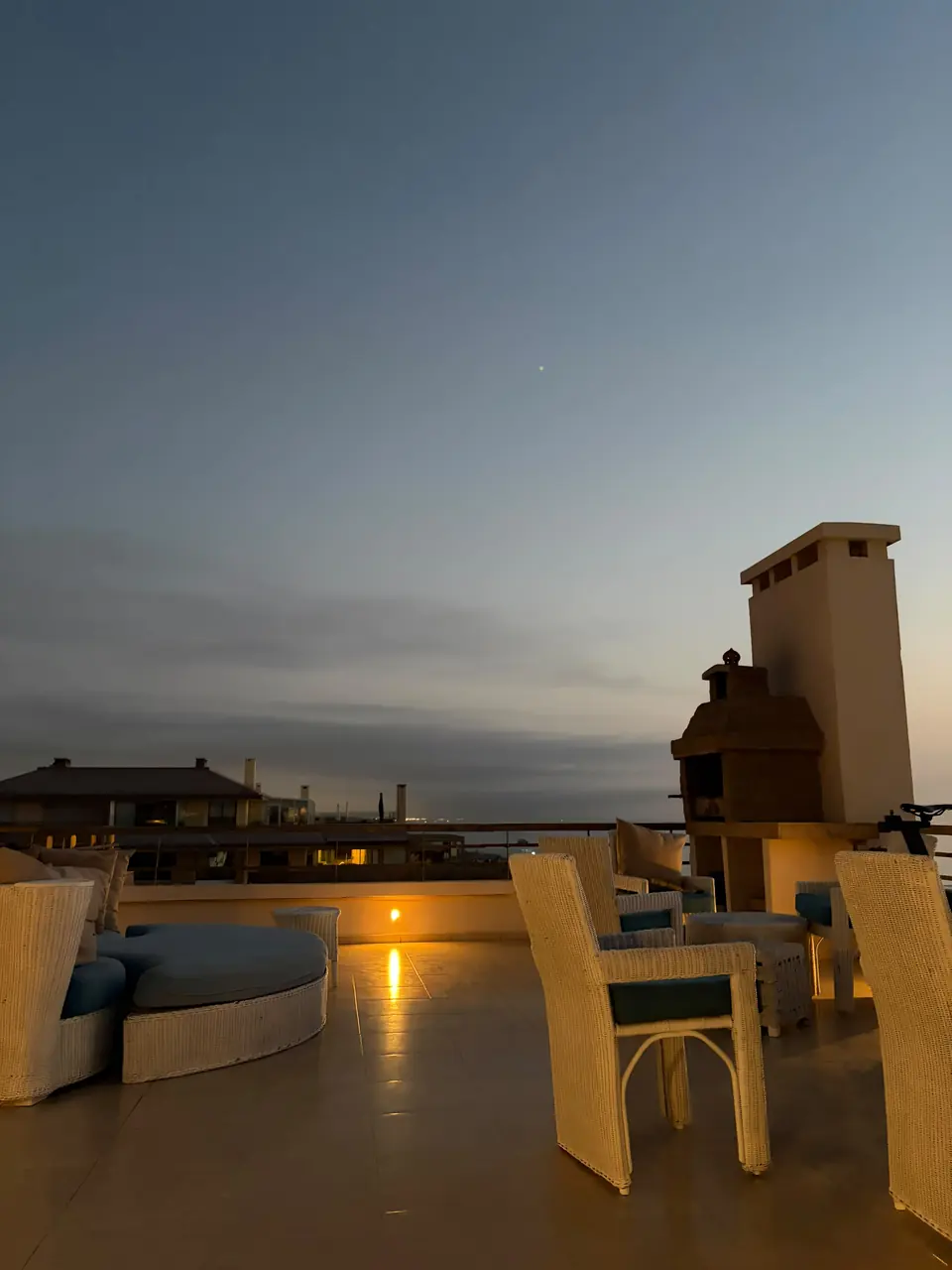Second salon d’extérieur de la terrasse au crépuscule, cheminée du barbecue en arrière-plan