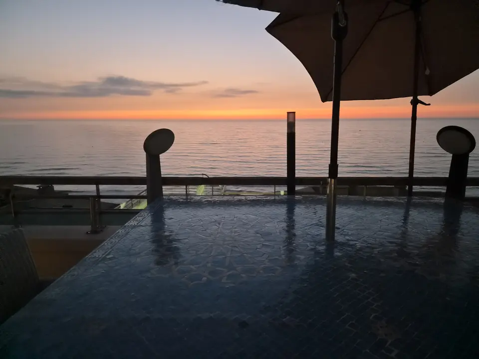 Table de la salle à manger d’extérieur face à l’océan au coucher du soleil
